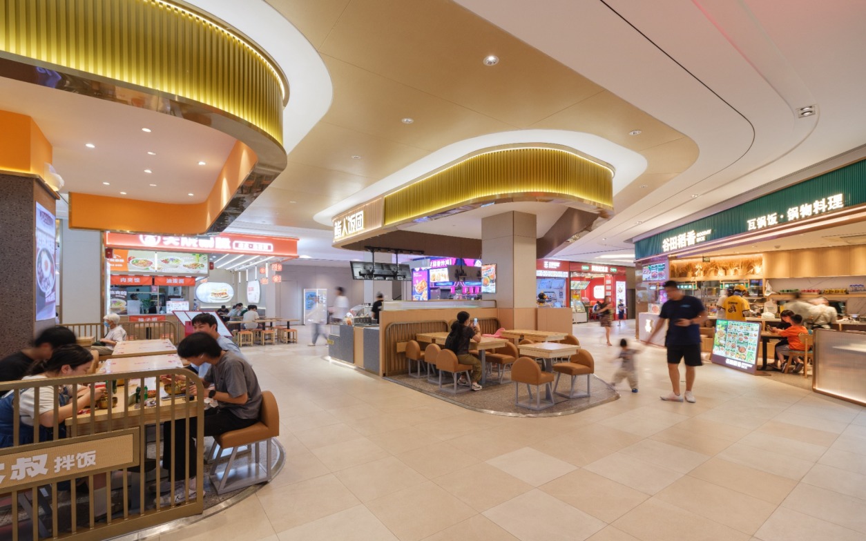 现代购物中心内部多层结构，透明玻璃天窗顶棚和扶梯连接各楼层。