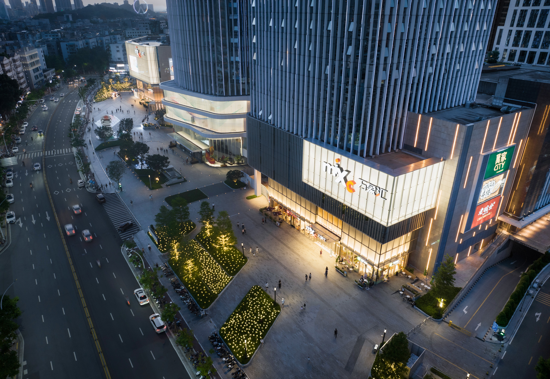 购物中心内现代圆形天花板，中央区域有三角形镜面装饰，周围环绕暖色灯光。