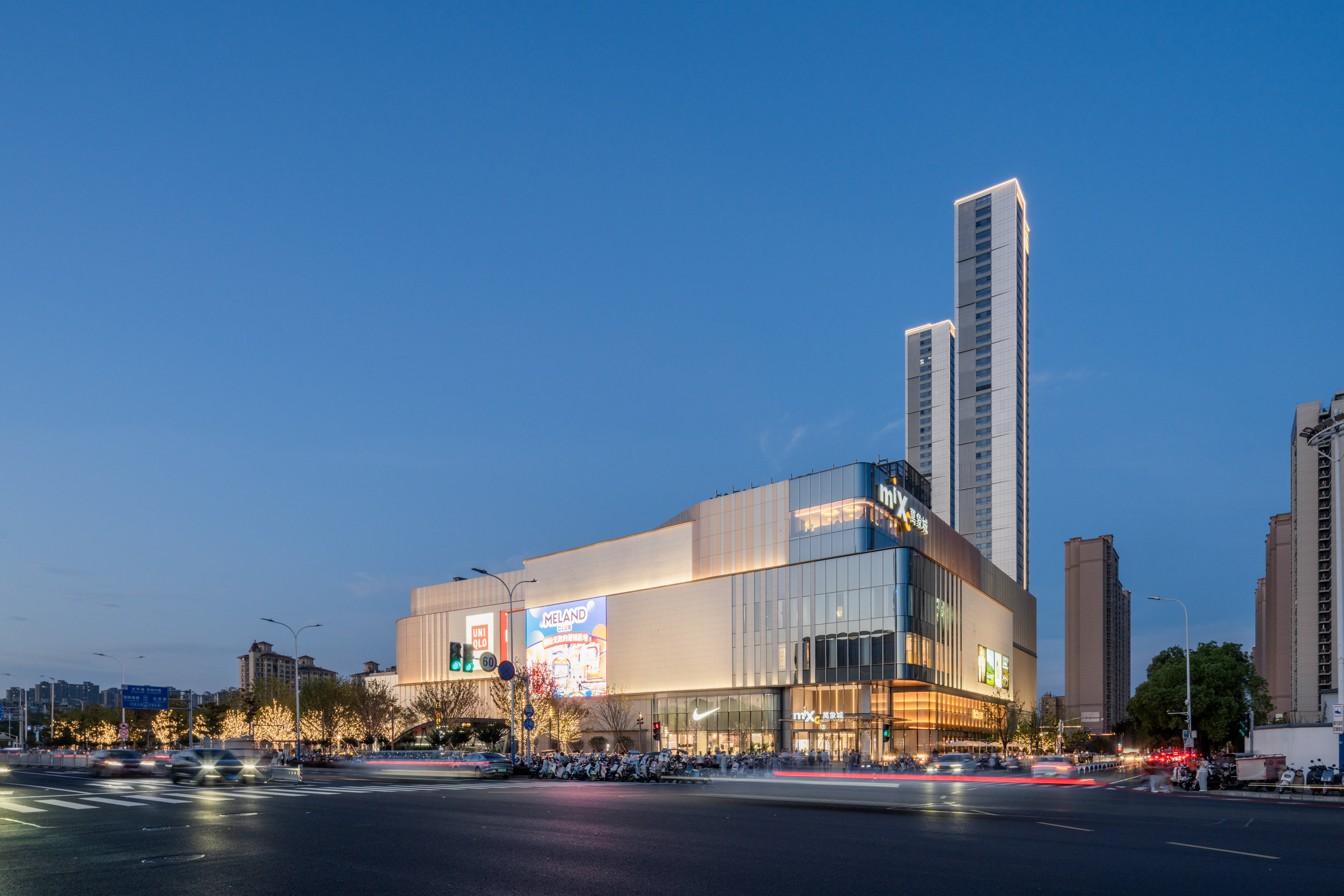 现代购物中心内，人们在明亮的走廊中行走，天花板装饰有圆环形灯光，商店包括Calvin Jeans和DISSONA。