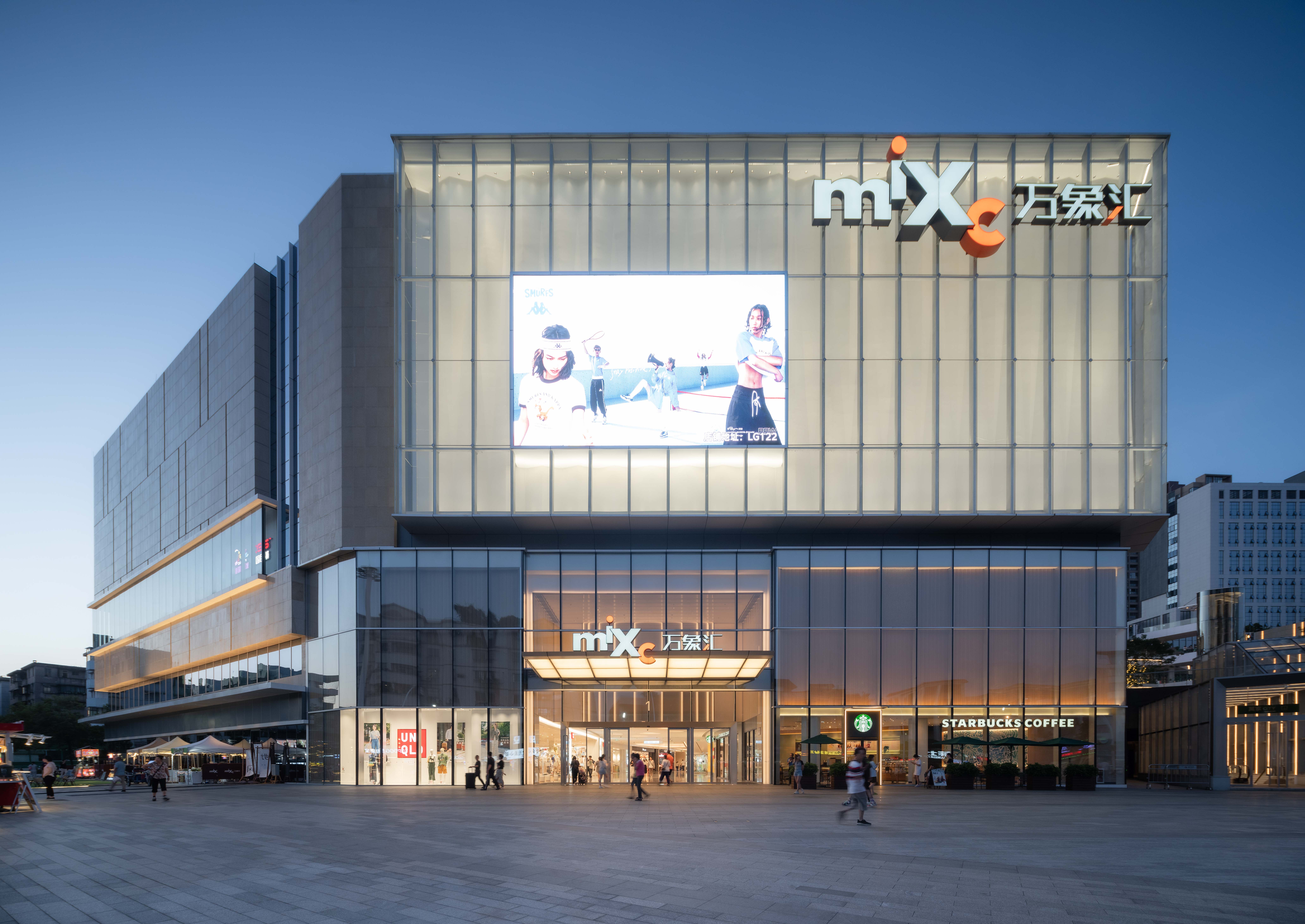 现代购物中心内部，中央有大型玻璃穹顶和多层环绕商铺，右侧有自动扶梯。