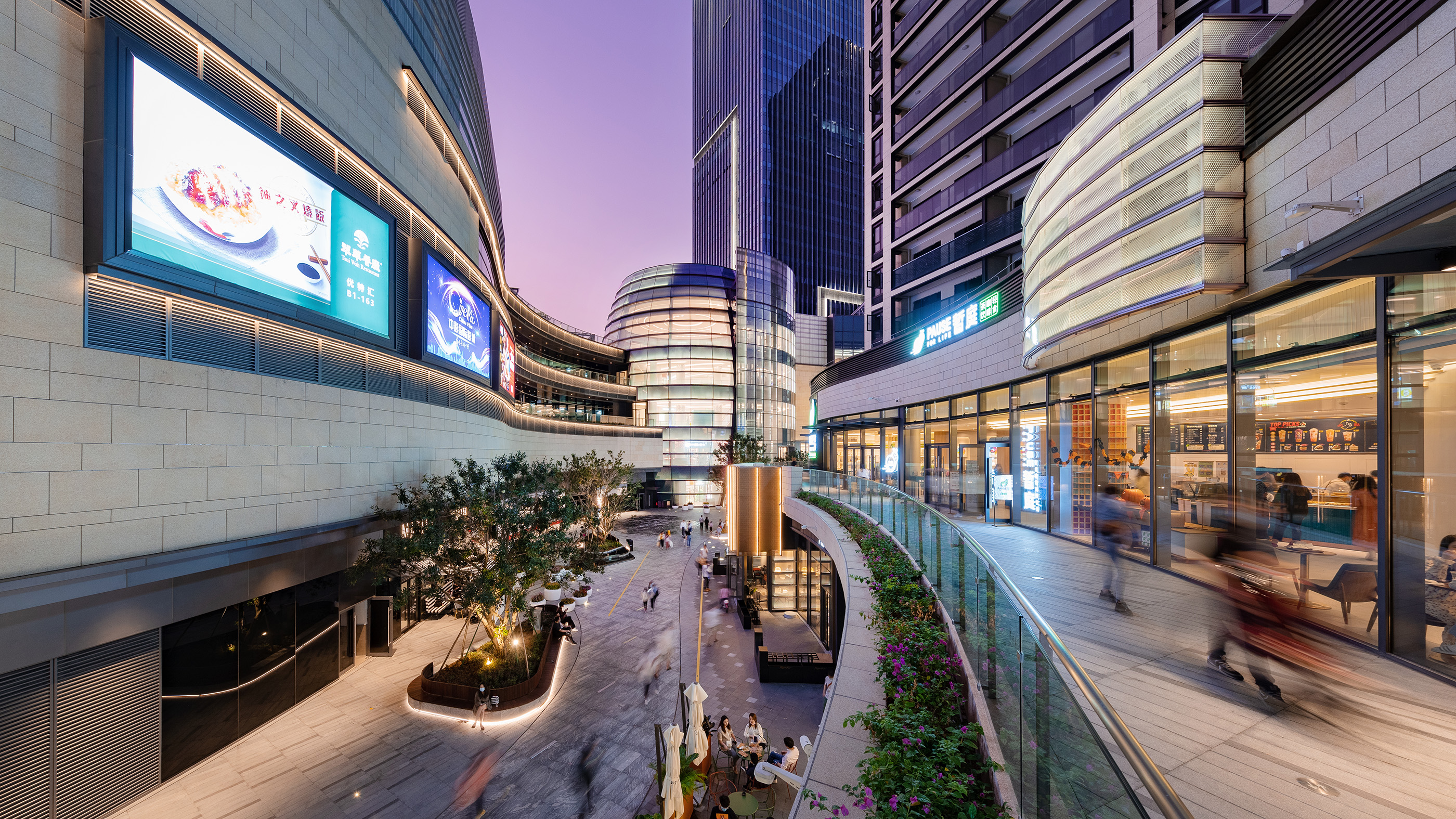 现代购物中心内部多层结构，透明玻璃天窗顶棚和扶梯连接各楼层。