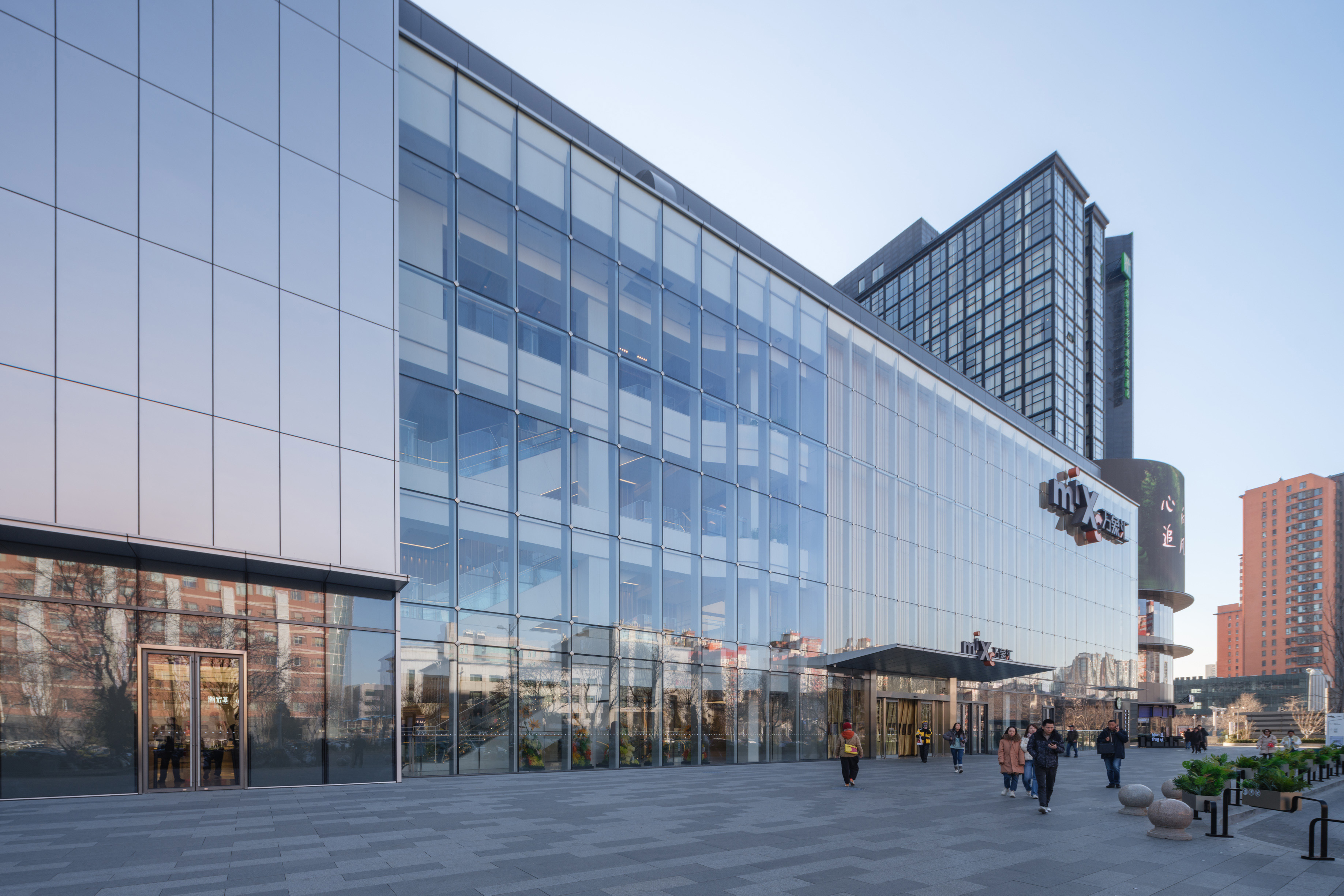 购物中心内现代圆形天花板，中央区域有三角形镜面装饰，周围环绕暖色灯光。