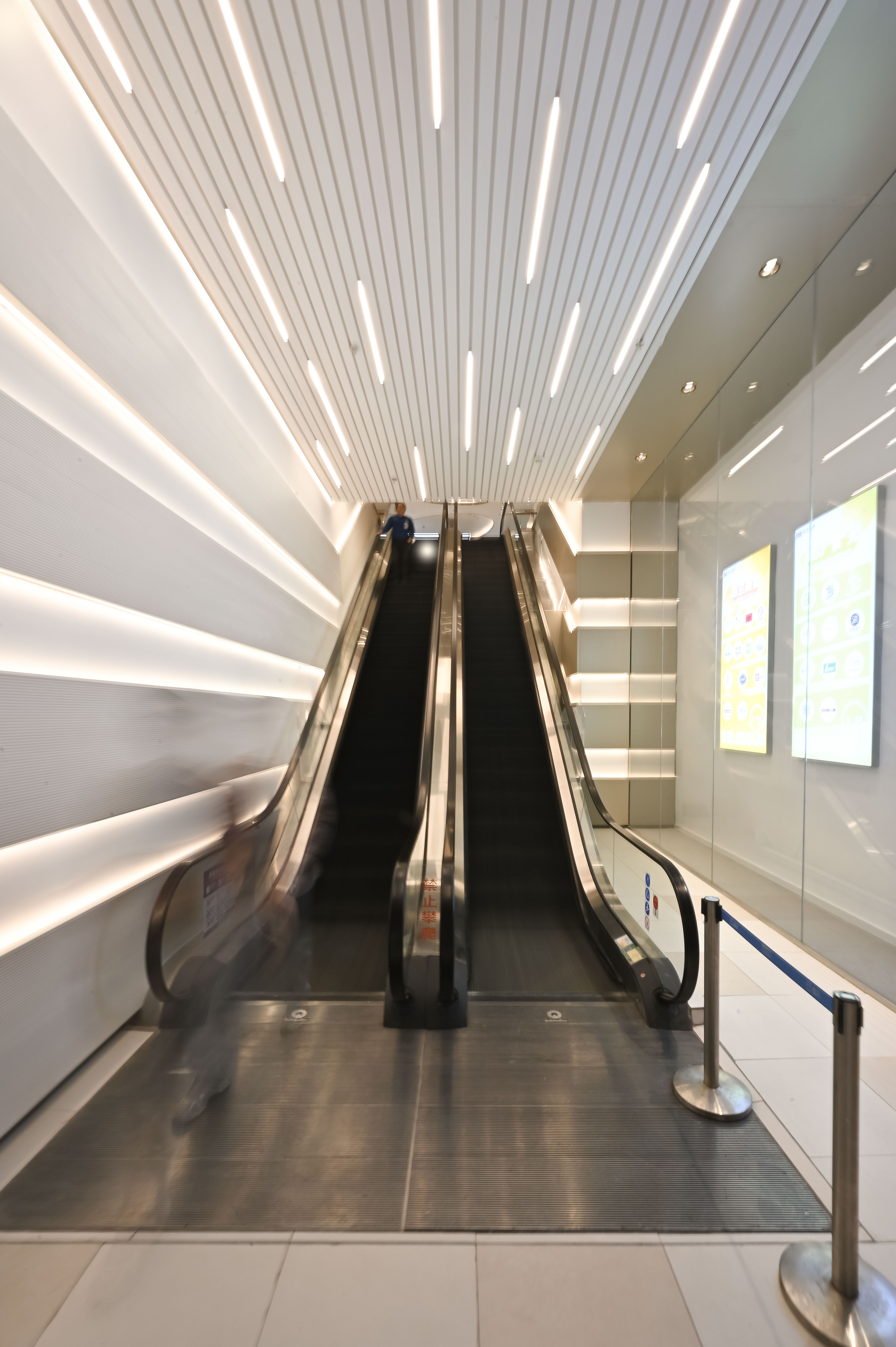 现代购物中心内部多层结构，透明玻璃天窗顶棚和扶梯连接各楼层。