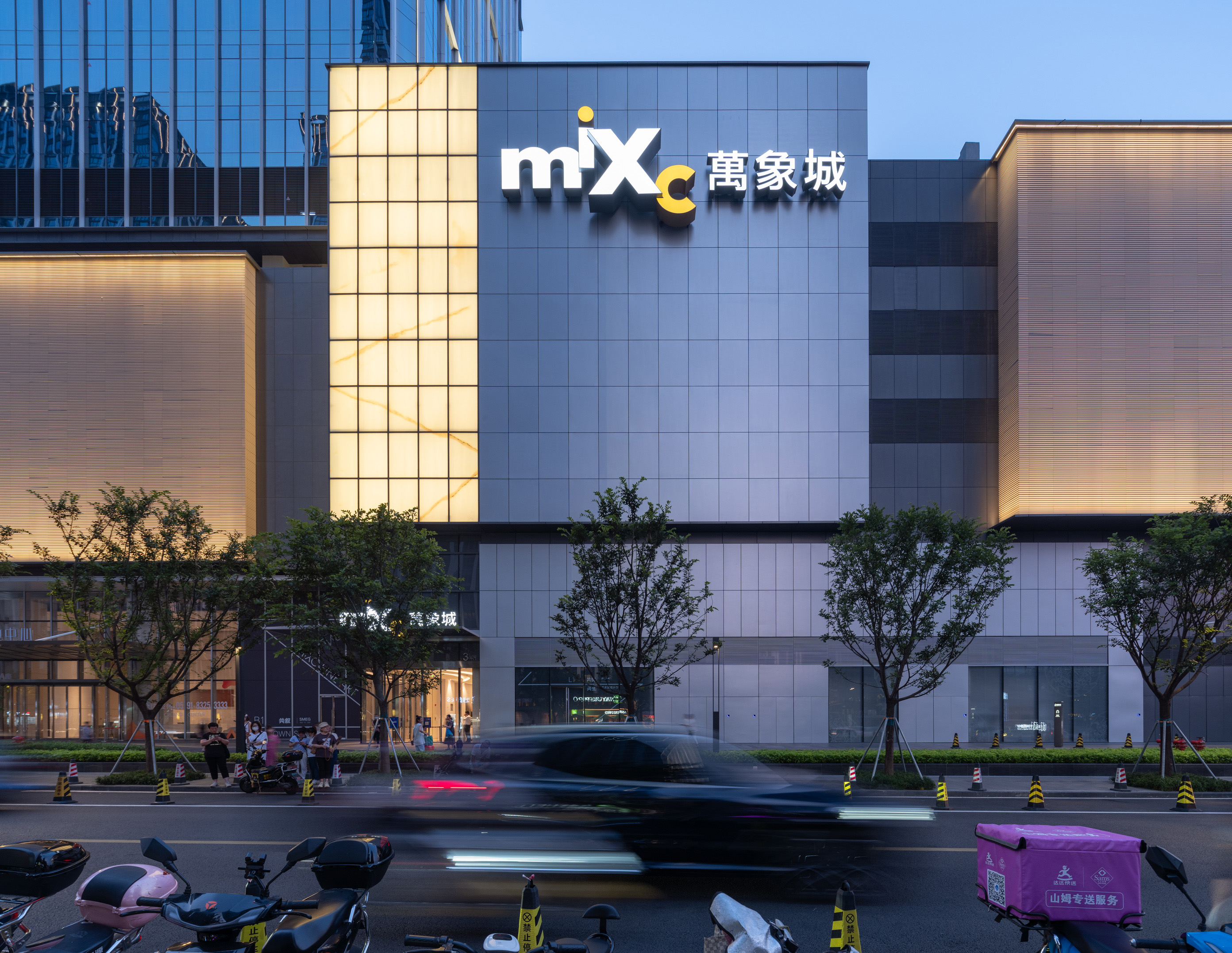 现代购物中心内，人们在明亮的走廊中行走，天花板装饰有圆环形灯光，商店包括Calvin Jeans和DISSONA。