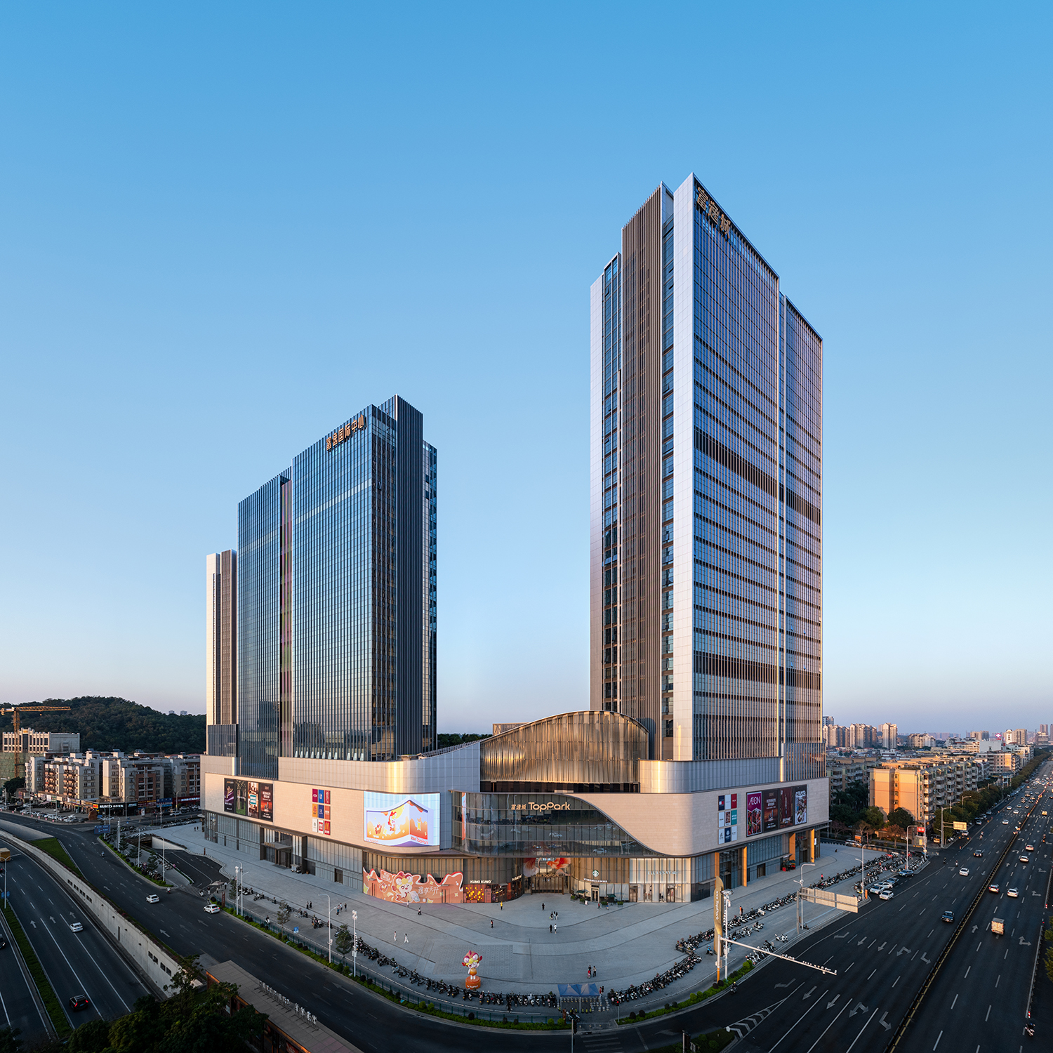 现代购物中心内部，中央有大型玻璃穹顶和多层环绕商铺，右侧有自动扶梯。